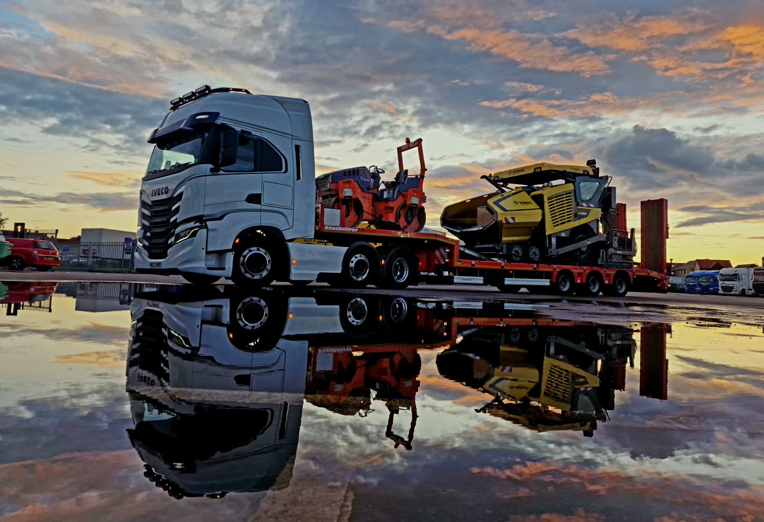 Loaded low loader reflected in standing water at sunset